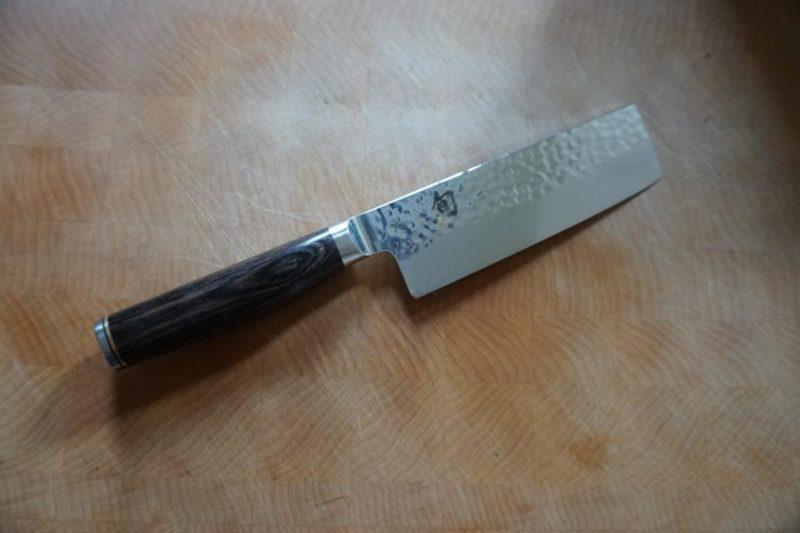 Close-up of a Shun Premier Nakiri knife on a wooden surface.