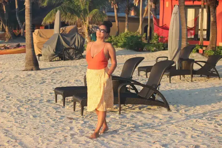 Woman standing on a sandy beach with chairs and umbrellas in the background