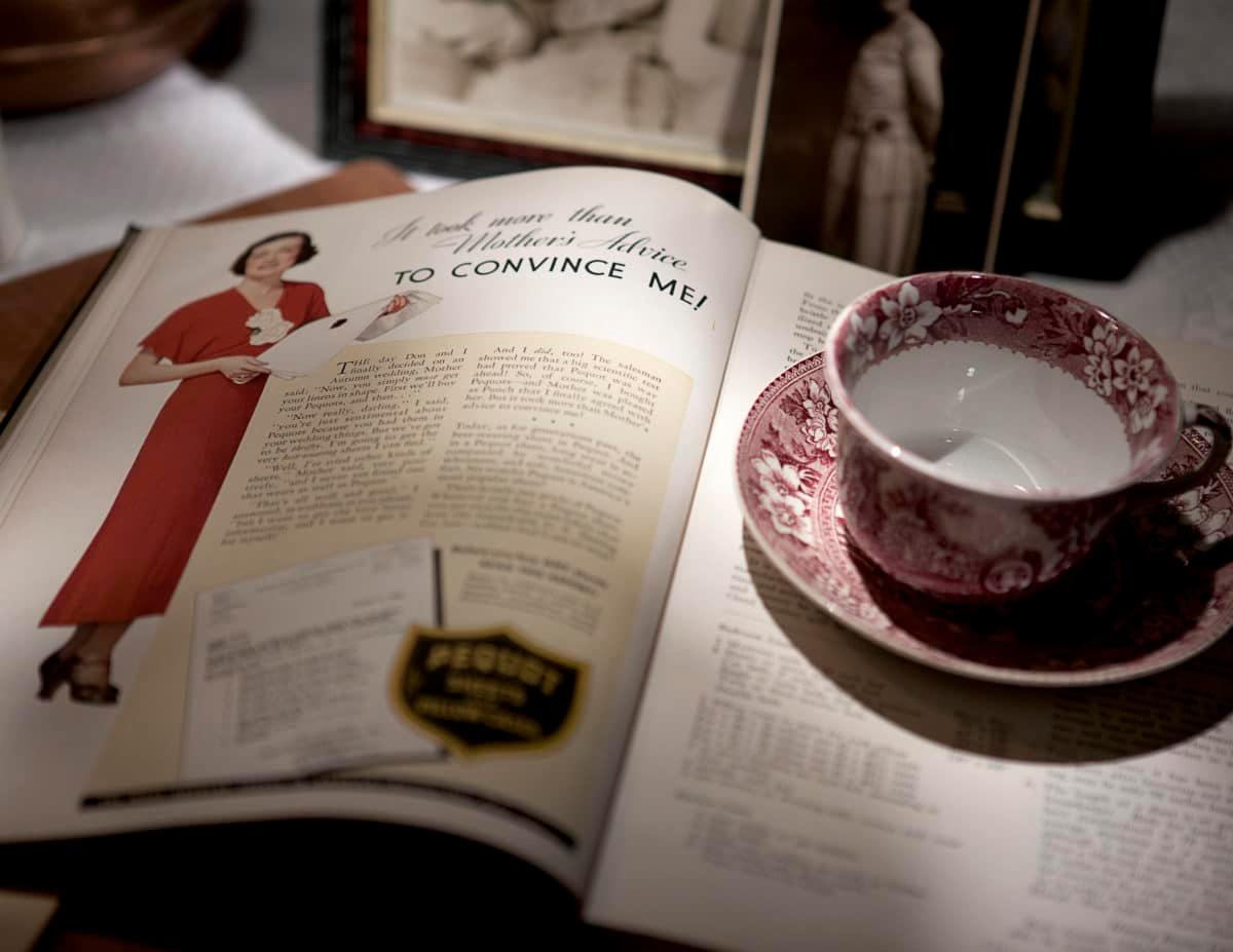 Vintage cookbook page displaying a woman in red attire and various text and advertisements.