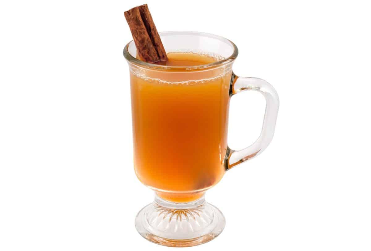 A glass mug of Cider Snap Mocktail with a cinnamon stick inside.