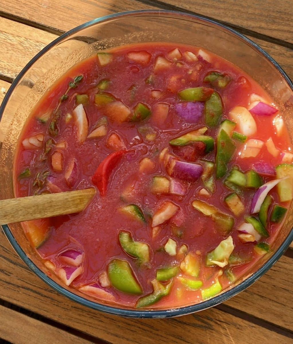 Bowl of gazpacho ingredients with various vegetables.